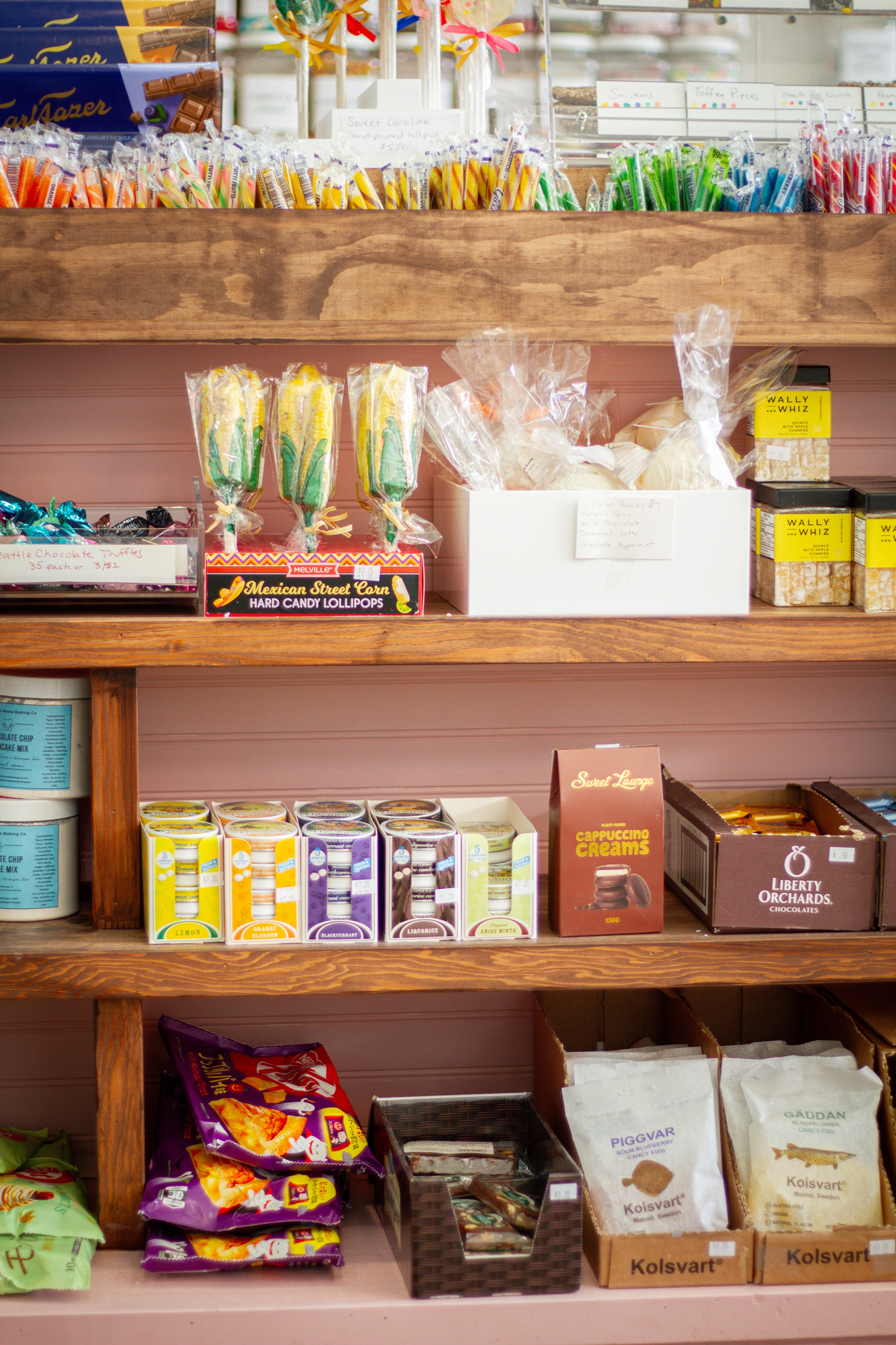 a shelf of various novelty candy items, including candy sticks, corn on the cob candy, capuccino cream, sour bluberry candy fish